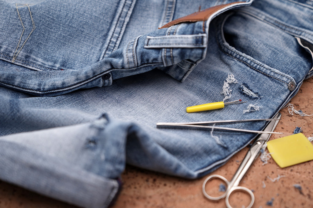 Old jeans and various sewing tools to illustrate reusing old clothes